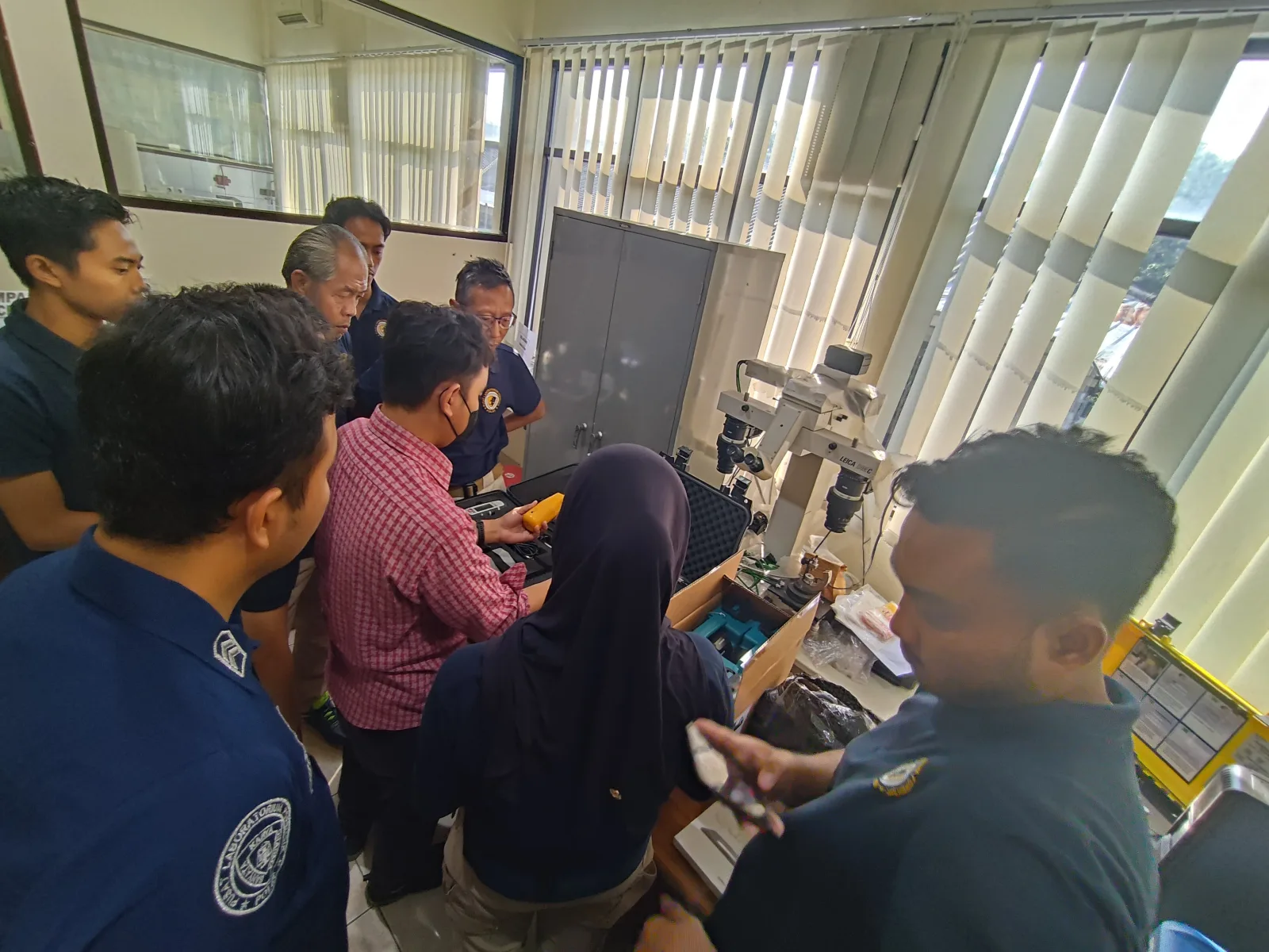Kelompok peserta pelatihan mengamati perangkat genggam di ruang laboratorium