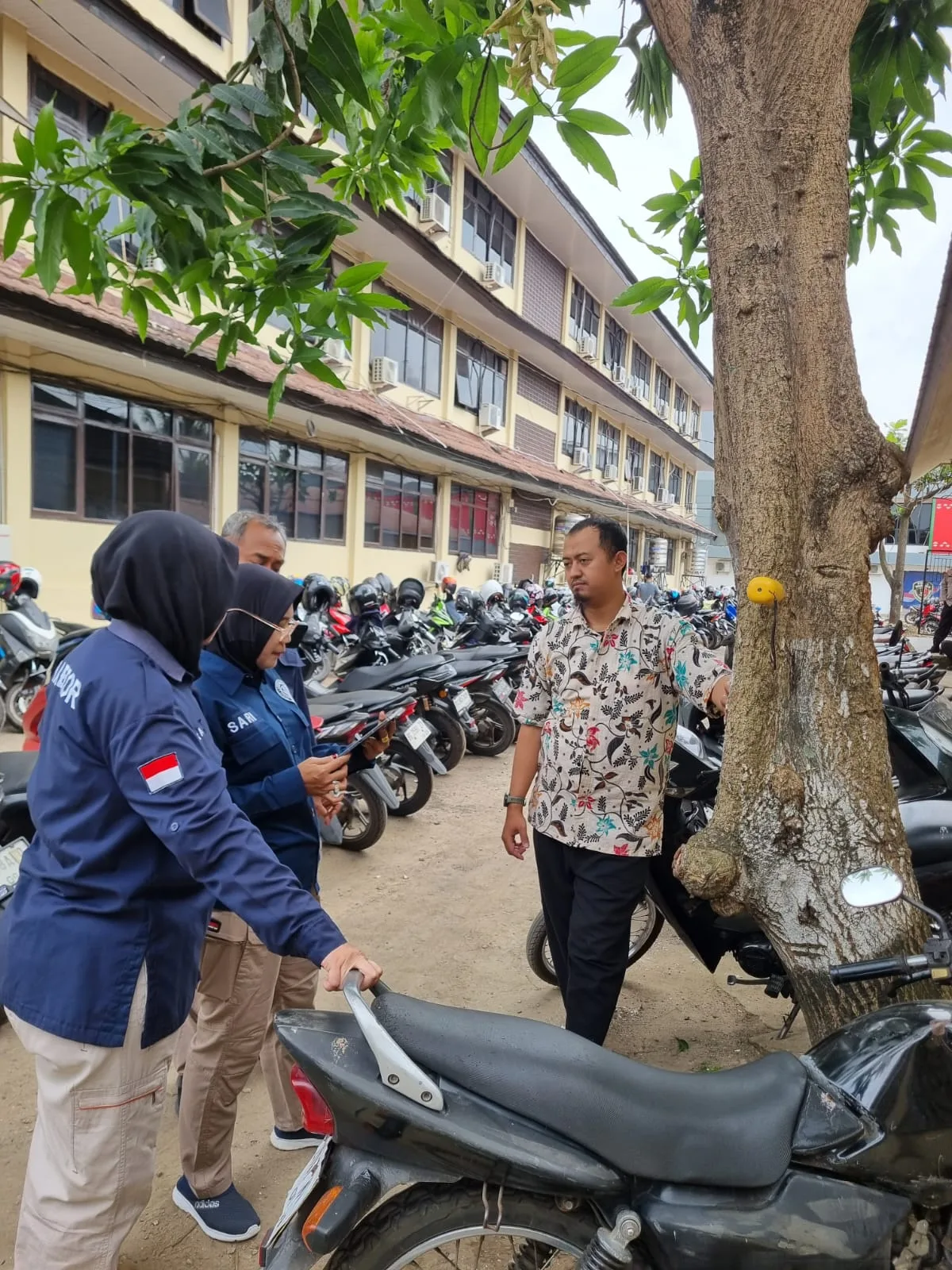 Peserta pelatihan berdiskusi di dekat batang pohon dengan titik kontak yang tampak pada kulit batang