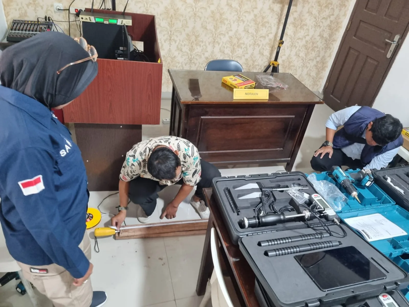 Peserta pelatihan mengukur dan menandai posisi pada spesimen kayu panjang di lantai