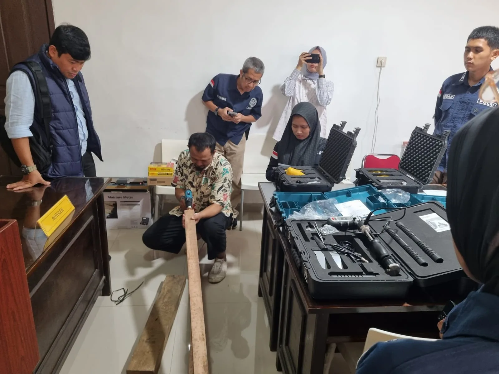Peserta pelatihan meninjau balok kayu yang diletakkan di lantai ruang praktik